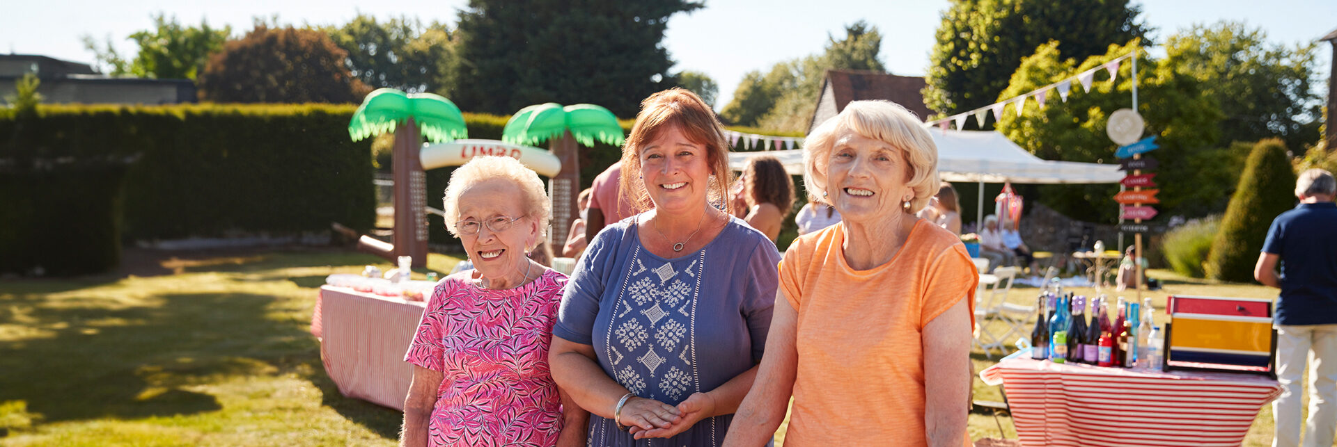 2 senior women with caregiver at an outdoor bbq